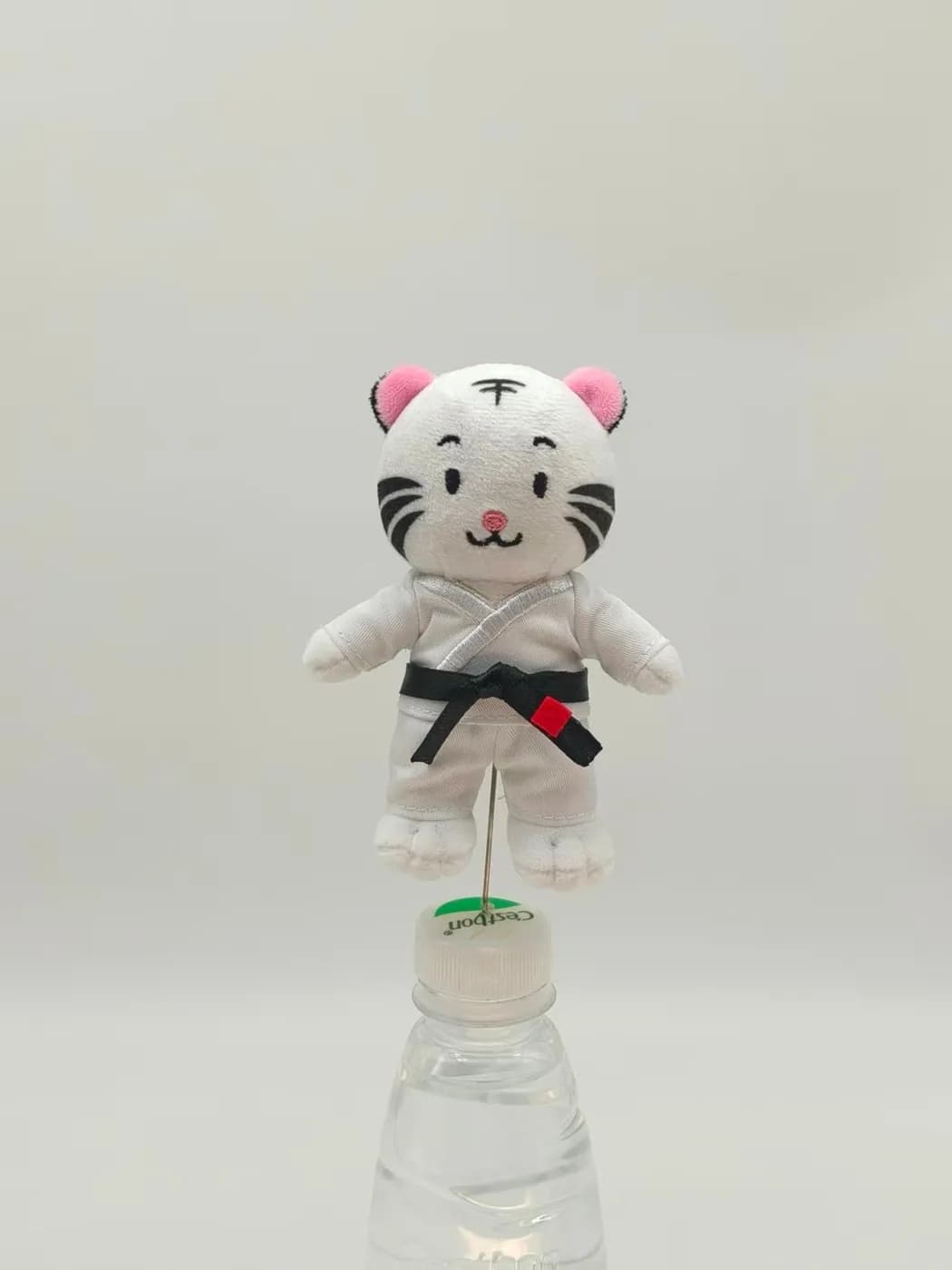 White tiger plush toy in a karate suit with a black belt