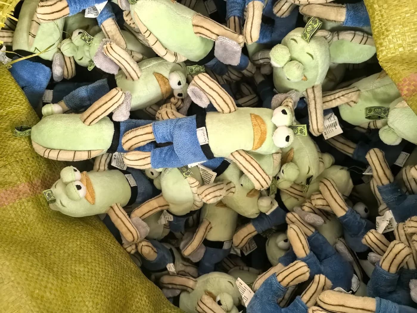 Bulk run of pale green and blue character charms on a sack