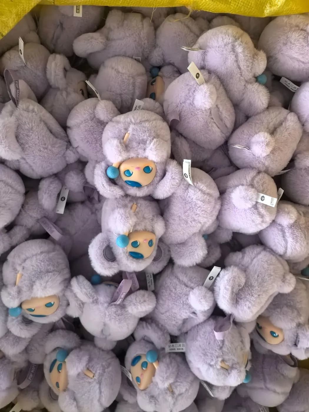 Bulk run of lilac curly-pile character charms with hangtags