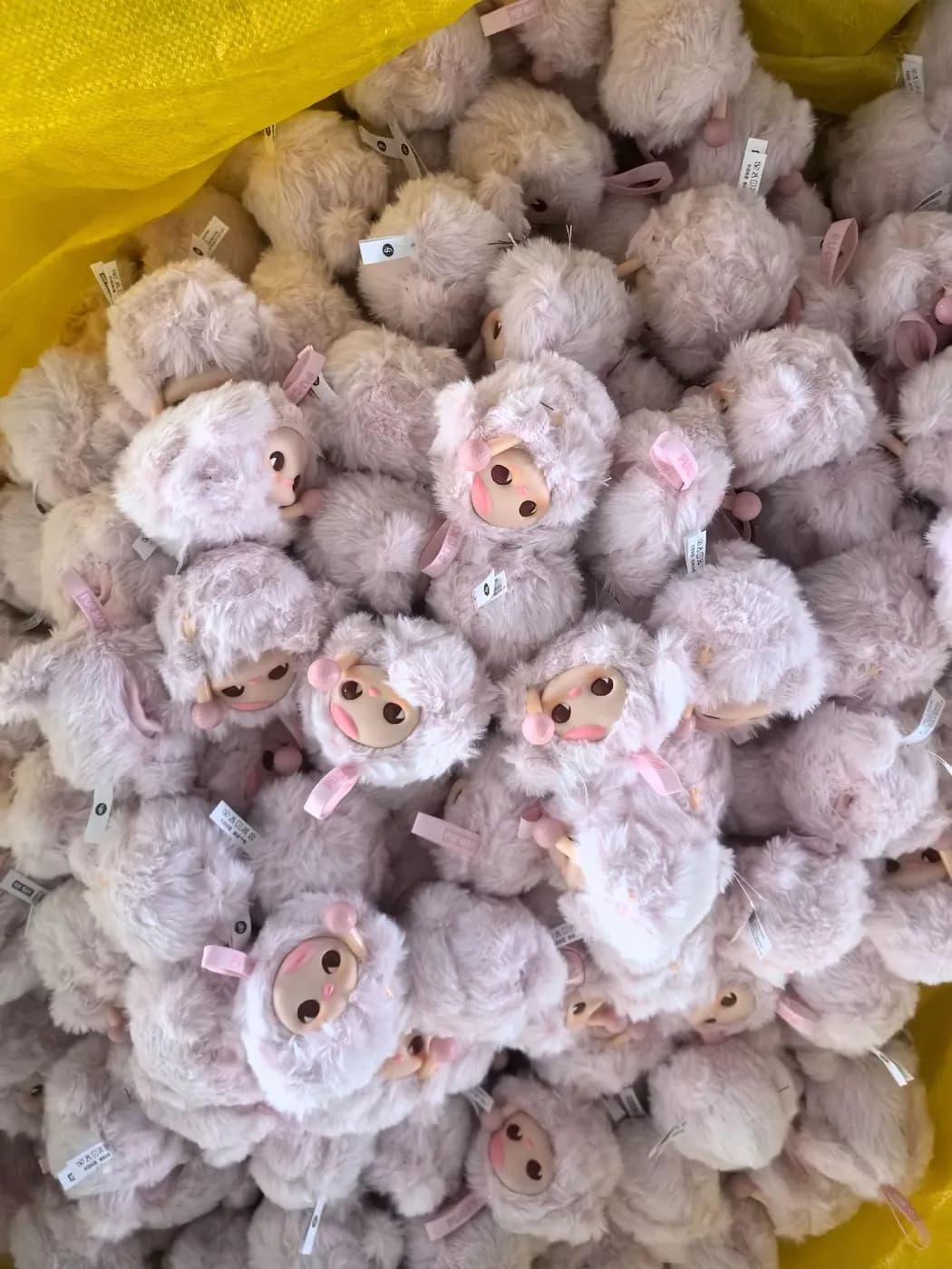 Pale pink curly-pile character charms piled on a sack after sewing