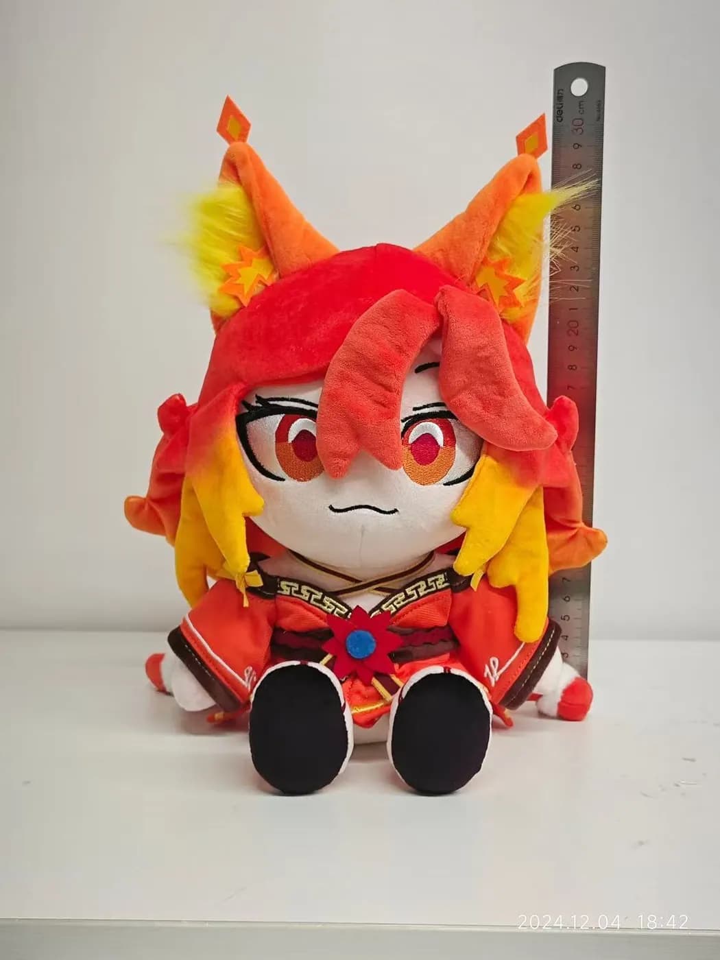 Character doll with flame-coloured hair and a printed festival costume