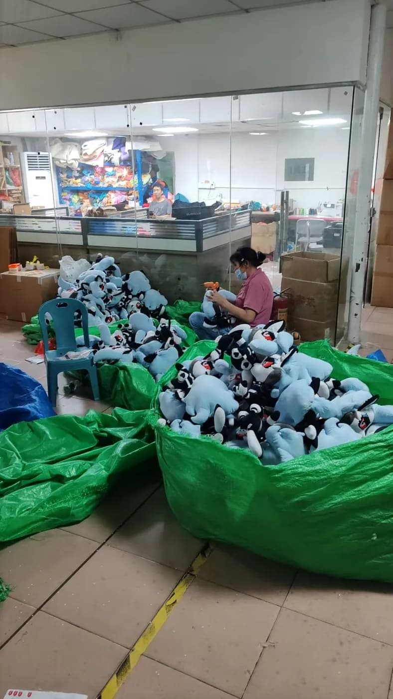 An operator sorting finished charms into sacks at the packing bench