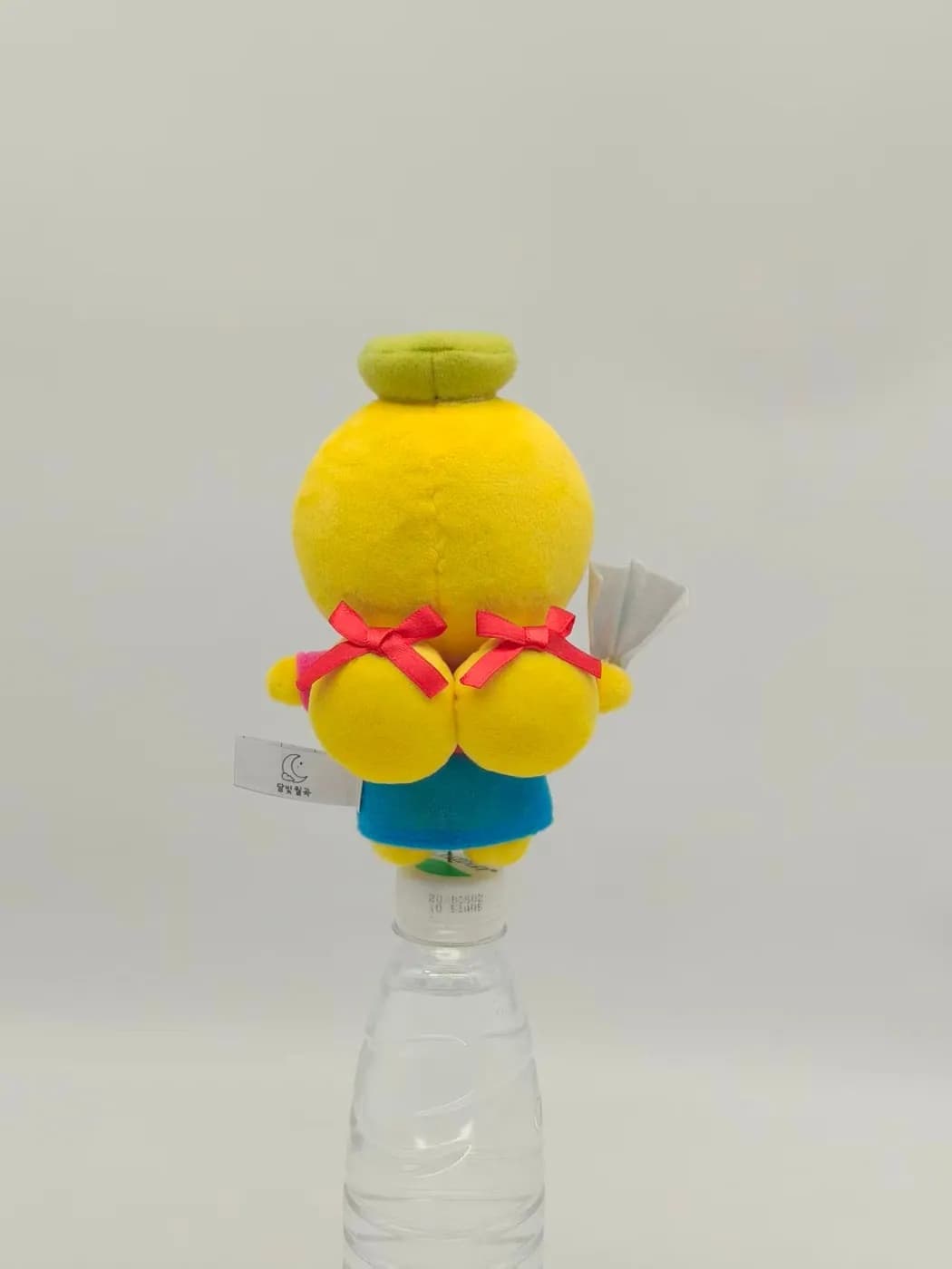 Yellow character mascot plush with red ribbon bows